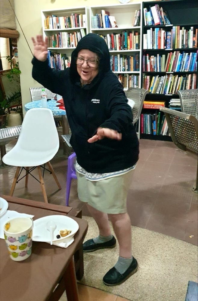 Nadia dancing in a black hoodie between the library tables