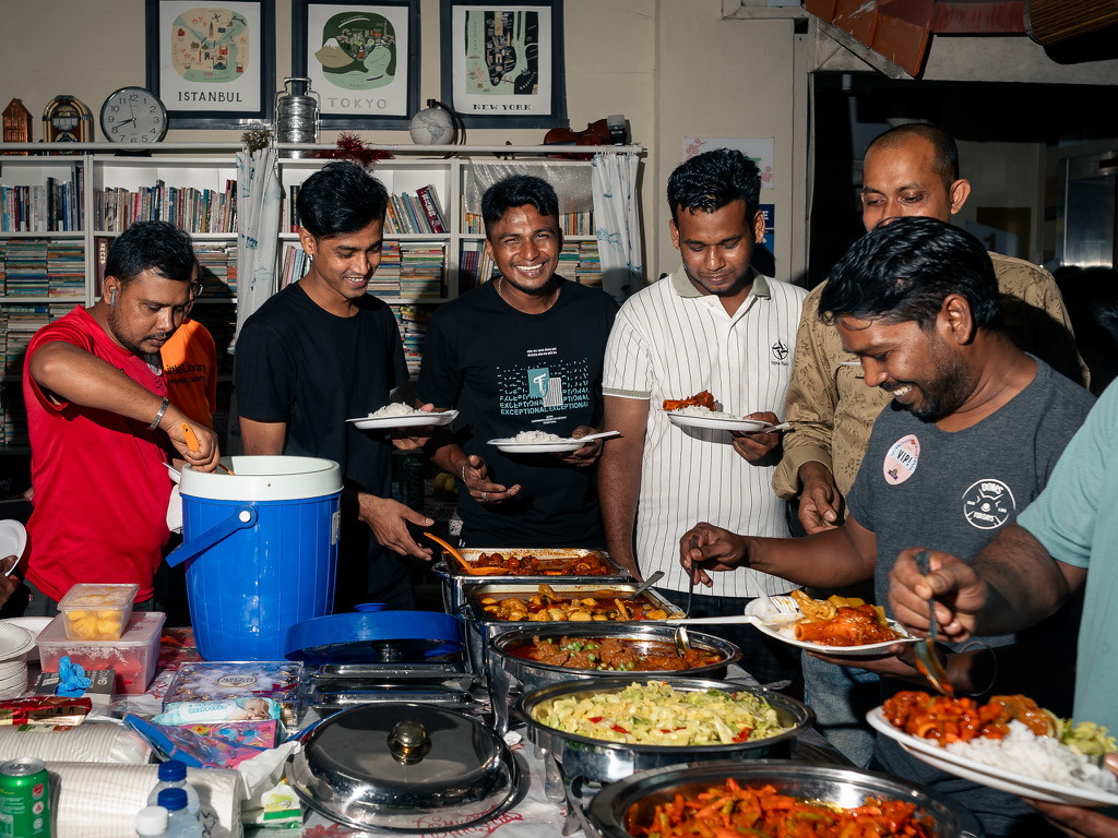 Neighbours serving themselves from a shared buffet inside the library